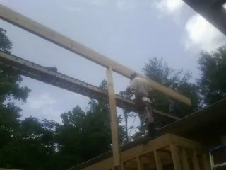 Carpenter setting a ridge beam over a new addition frame — Ice Dam Removal by Roofing Brothers in Hopkinton