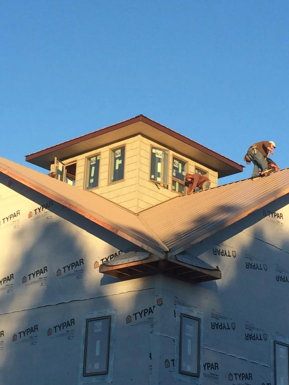 Roofers working around a rooftop cupola on a new metal roof at sunset — Roof Waterproofing in Hopkinton by Roofing Brothers